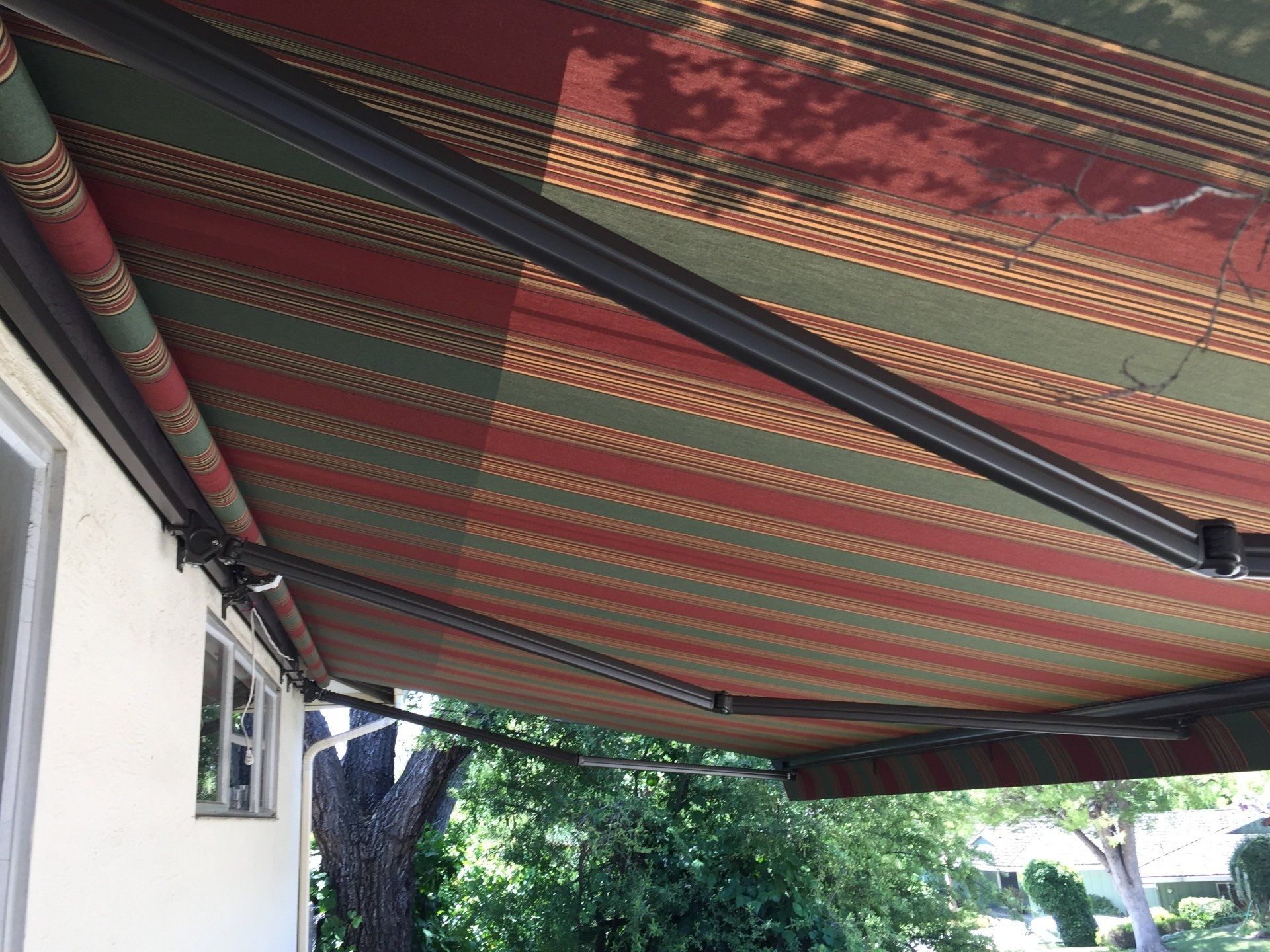 A red and green awning is hanging from the roof of a house.