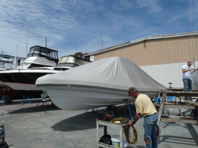 A man is working on a boat with a cover on it