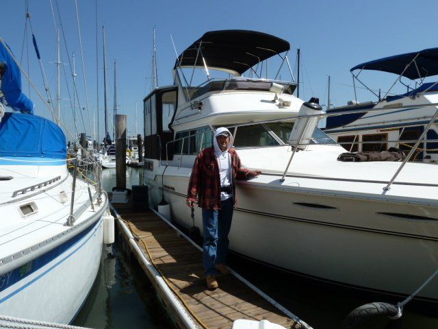 A man standing next to a boat that has the word corsair on it