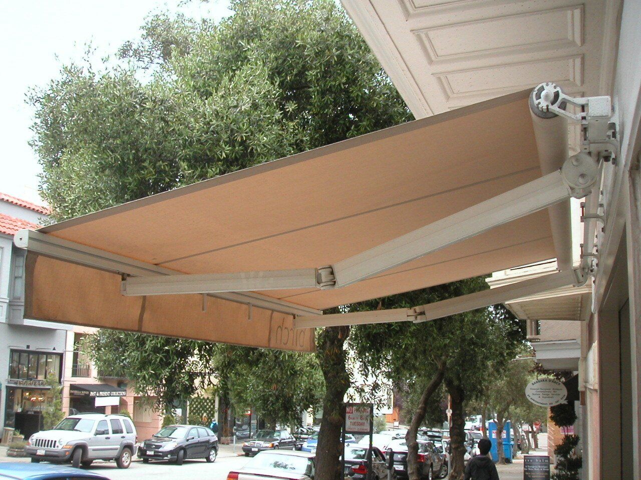 A tan awning is hanging from the side of a building