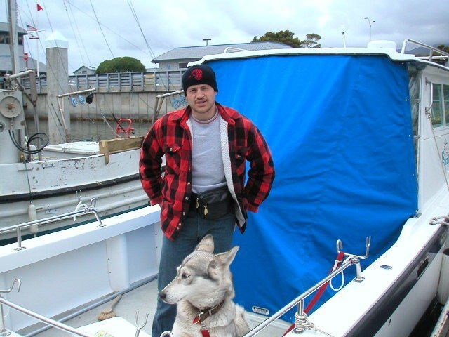 A man standing next to a dog on a boat