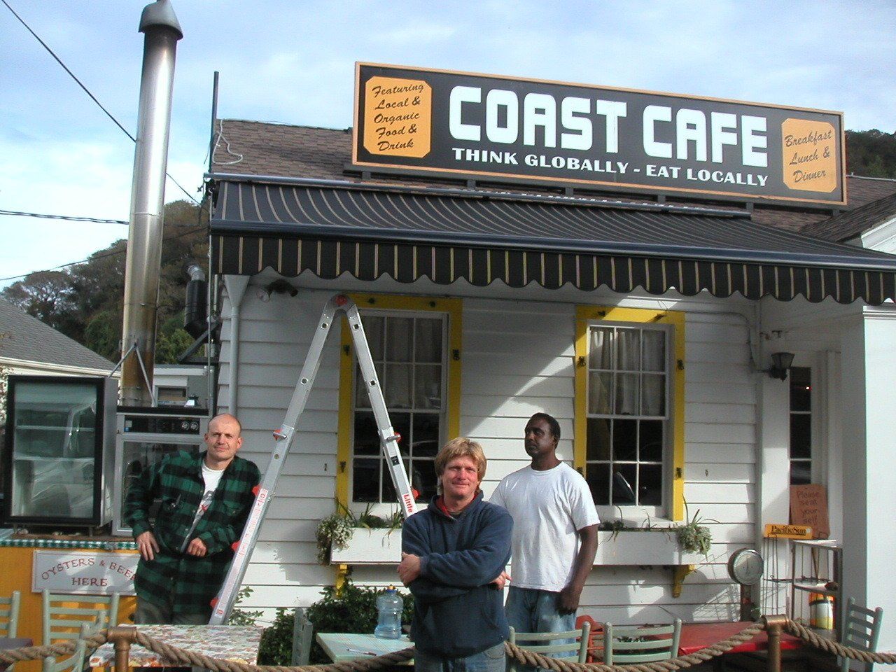 Three men stand in front of the coast cafe