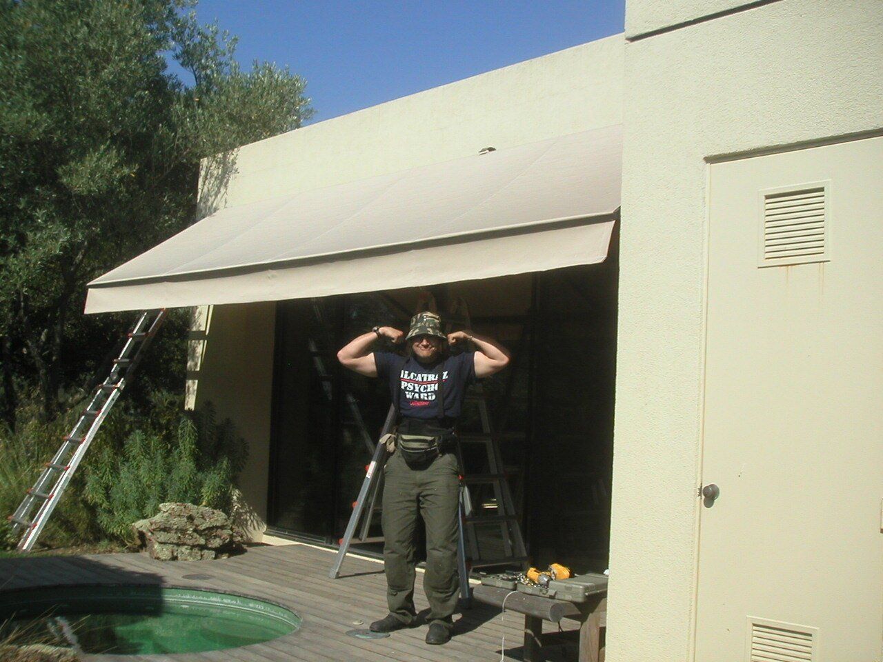 A man wearing a t-shirt that says free standing under an awning