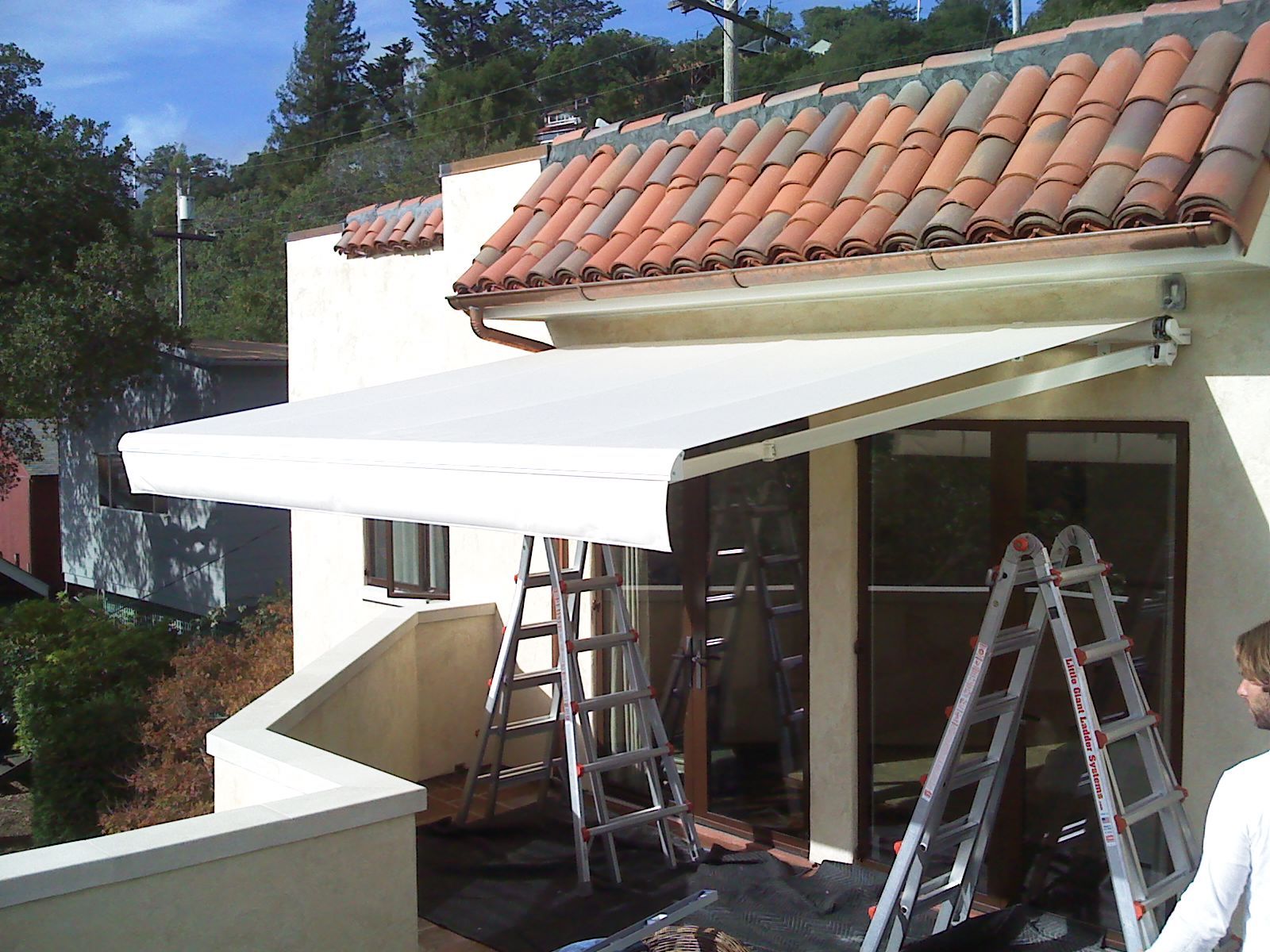 A white awning is being installed on the side of a house