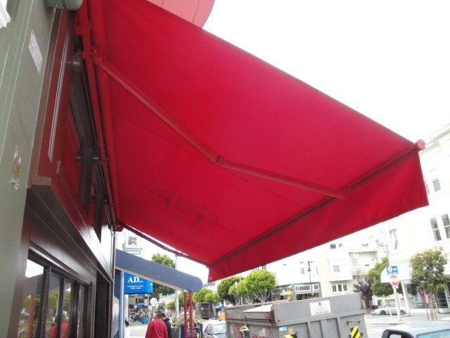 A red awning is hanging from the side of a building