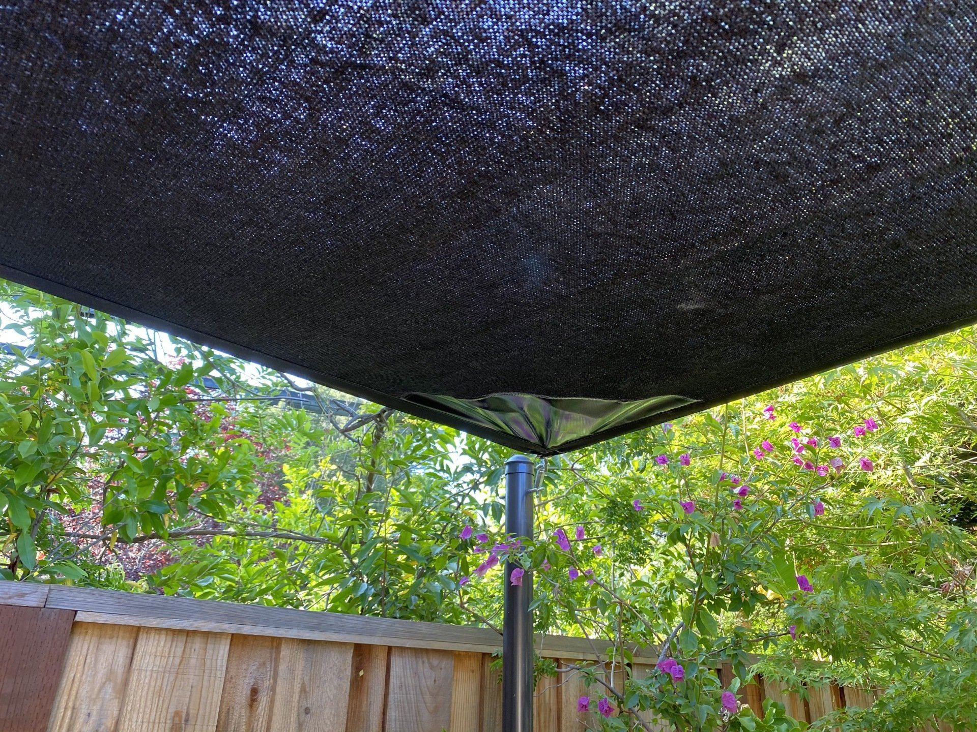 A black umbrella is sitting in front of a wooden fence