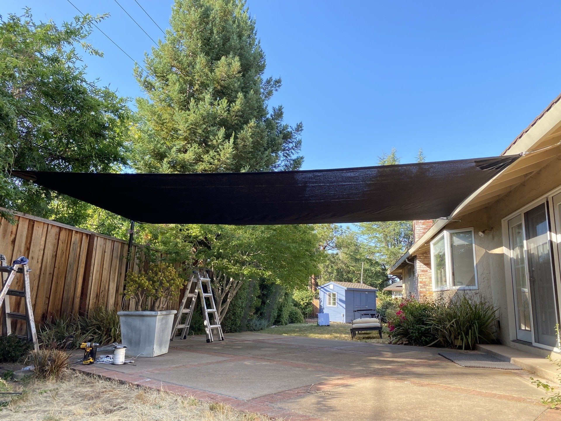 A black canopy is covering a driveway in front of a house.