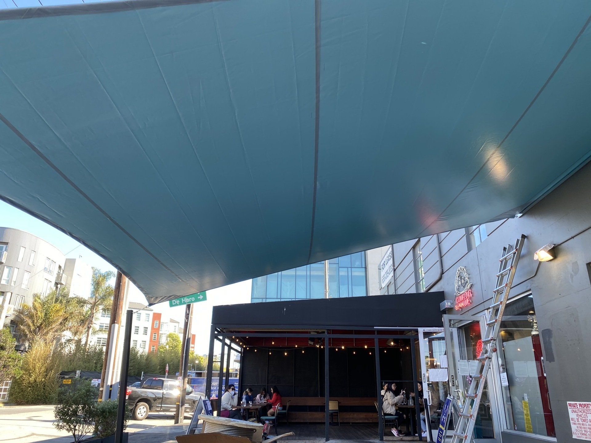 A group of people are sitting under an umbrella in front of a building.