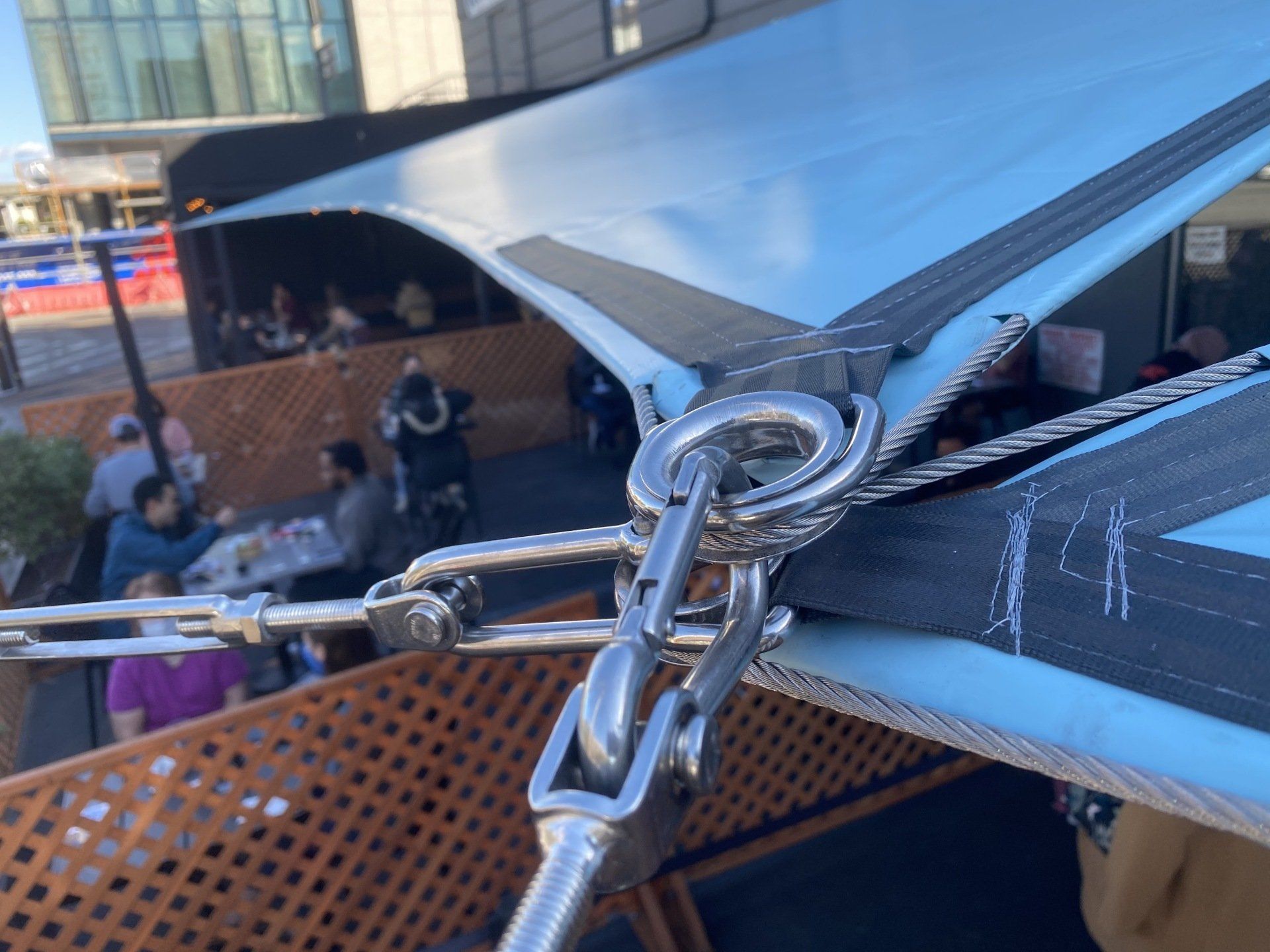 A group of people are sitting at tables under an umbrella.