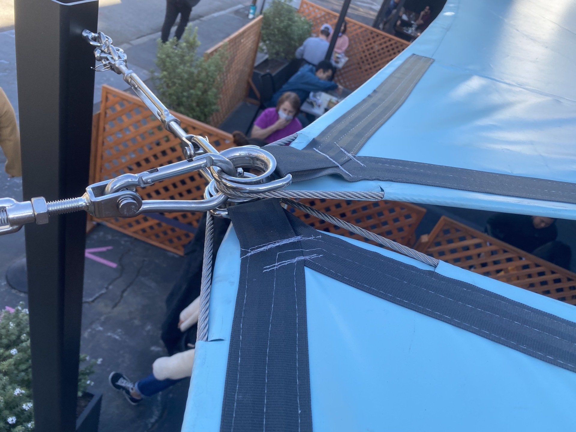 A group of people are sitting under a blue umbrella.