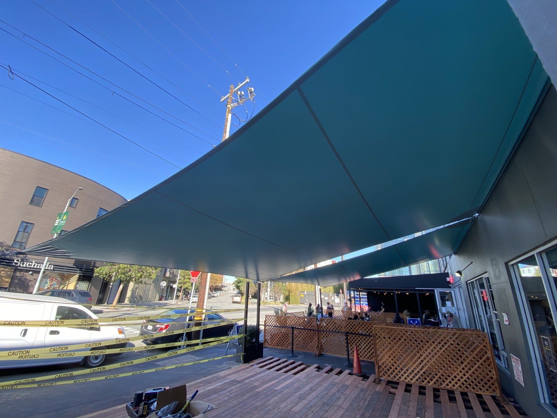A large green umbrella is sitting on top of a wooden deck.