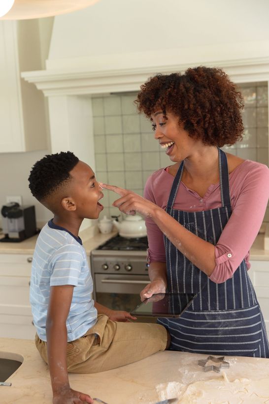 A woman is feeding a young boy in a kitchen.