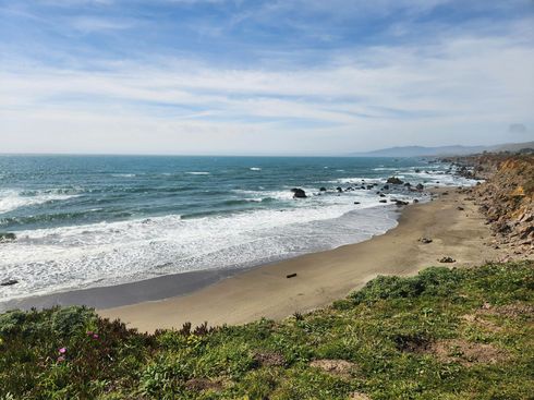 A beach with waves crashing against the shore on a sunny day.