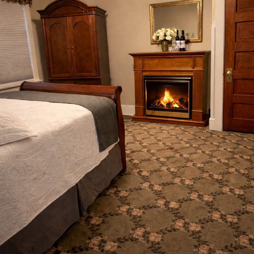 A bed with white bedding, headboard, and decorative spread, in a bedroom with artwork and a lamp.