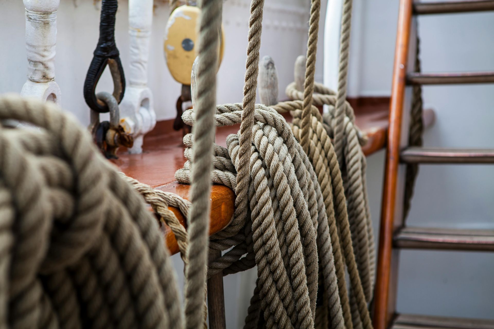 Coiled ropes on a wooden ship deck, near a wooden ladder and hardware.