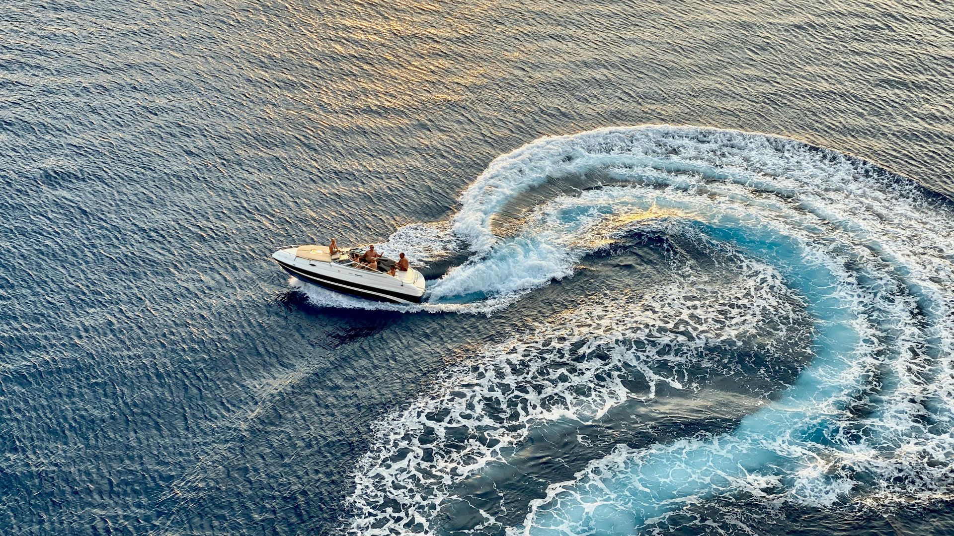 Motorboat navigating on water, leaving a foamy white trail. Passengers visible on board.
