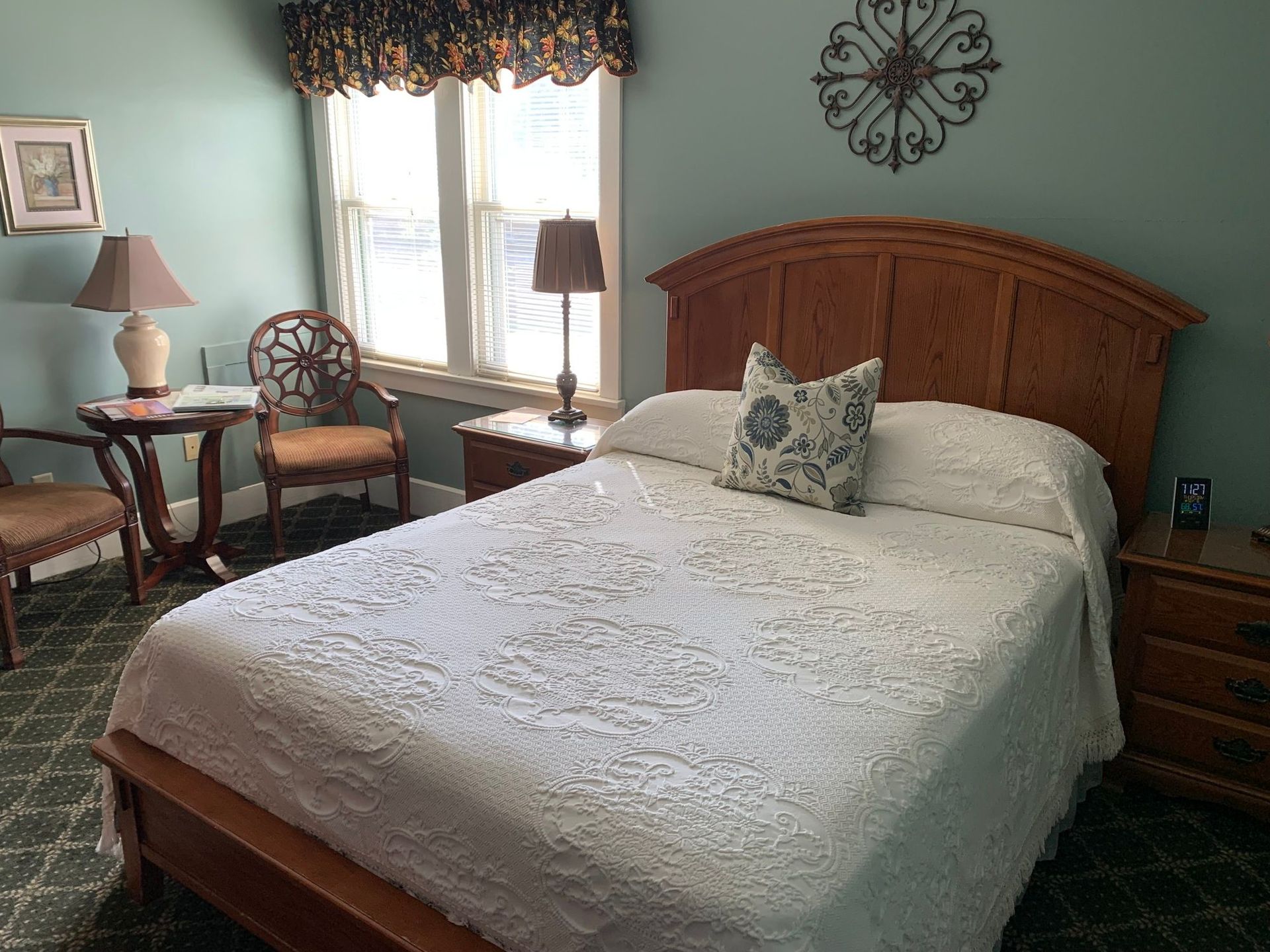 Bedroom with a wooden bed, nightstands, a small table with chairs, and a window.