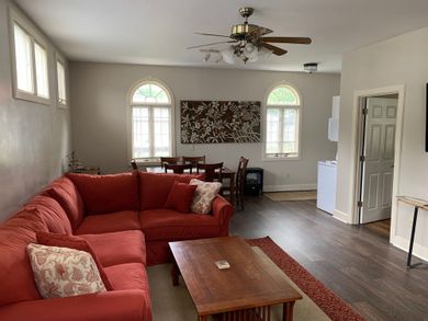 Living room with red sectional sofa, wooden coffee table, dining table, and arched windows.