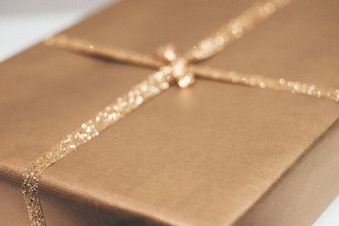 Gold wrapped gift box tied with glittery gold ribbon.