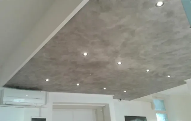 Soffitto grigio testurizzato con luci da incasso, sopra una stanza bianca con aria condizionata.