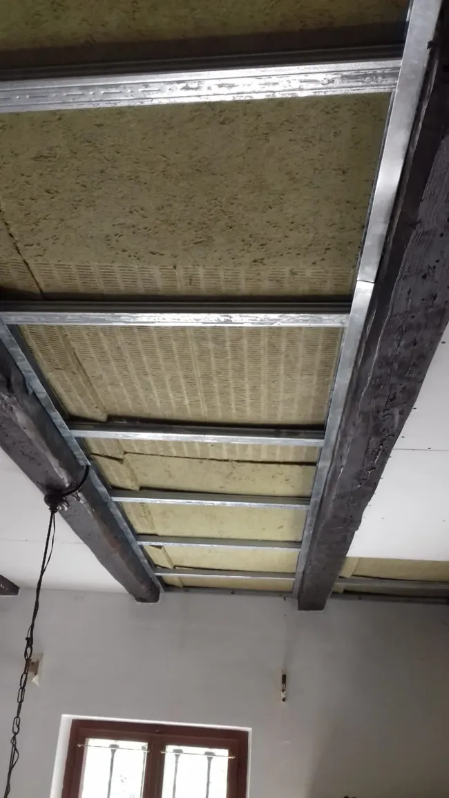 Telaio del controsoffitto in griglia metallica con isolamento, potenzialmente insonorizzante.