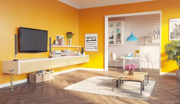 Soggiorno con pareti arancioni, TV sospesa, mensola beige, tappeto e porta che conduce alla zona pranzo.