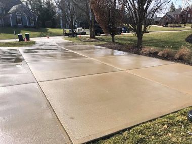 Wet concrete driveway slabs in a suburban neighborhood after rain.