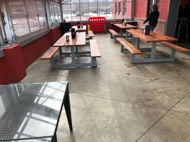 Empty cafeteria with wooden tables, red walls, and one person standing near the back.