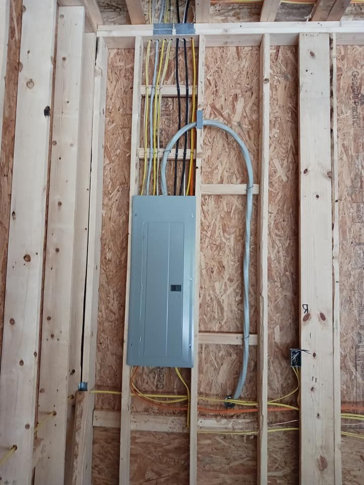 Electrical panel installed in a wooden wall frame with multiple wires running throughout.