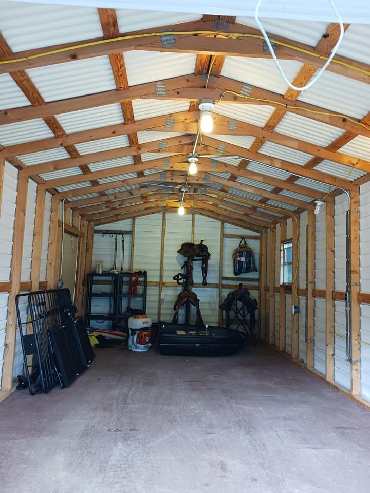 Interior of a wooden shed with tools, equipment, and overhead lighting.