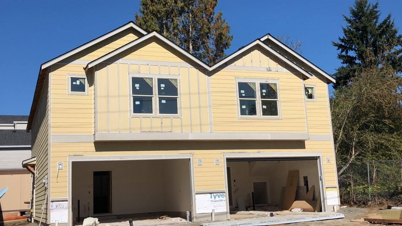 A house is being built with a garage and a lot of windows.