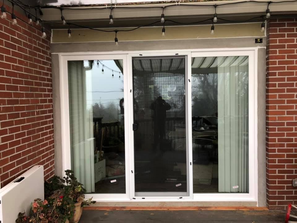 A sliding glass door is sitting on the side of a brick building.