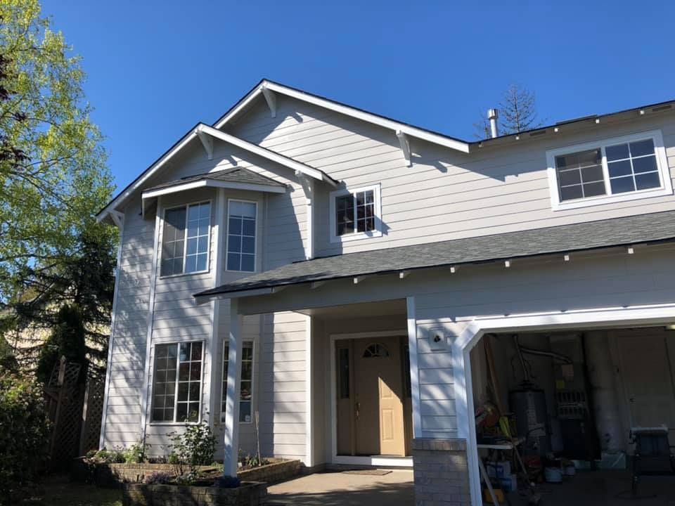 A large white house with a garage and a blue sky in the background.