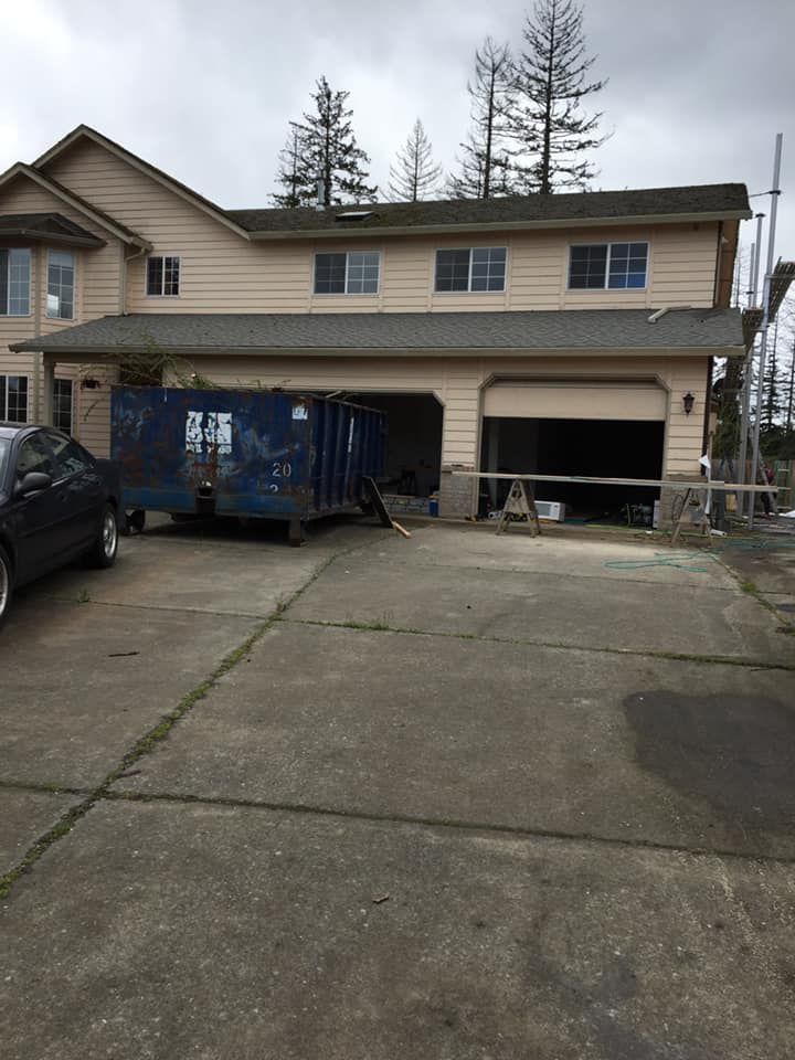 A large house with a blue dumpster in front of it.