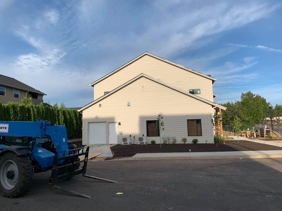 A blue forklift is parked in front of a house.