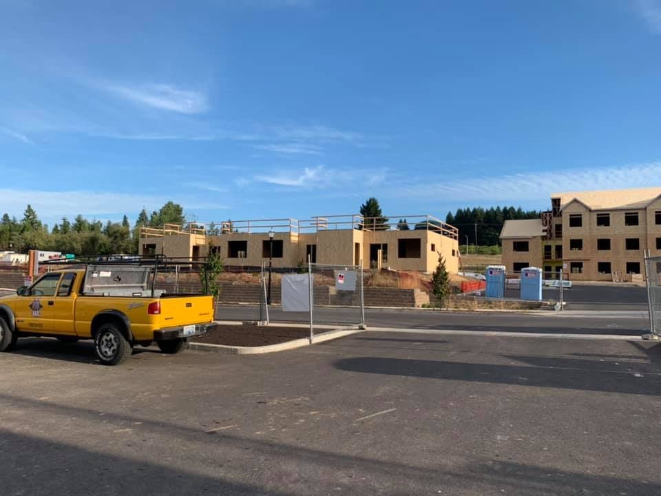 A yellow truck is parked in front of a building under construction.
