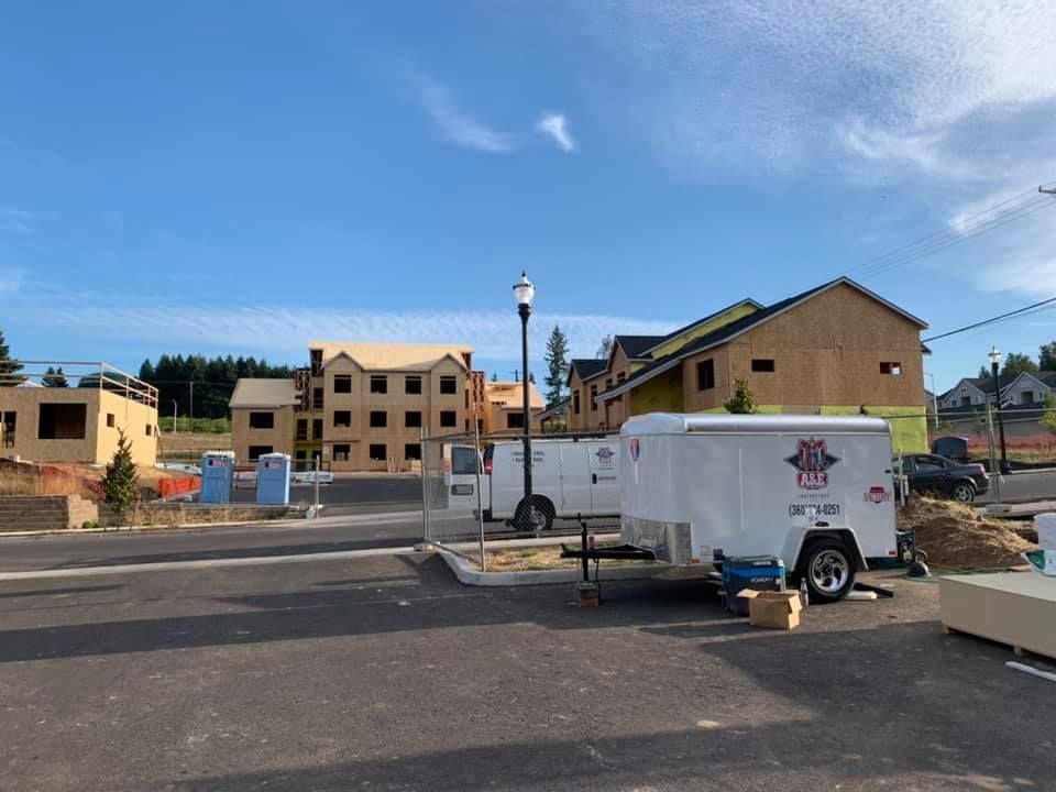 A white trailer is parked in a parking lot in front of a building under construction.