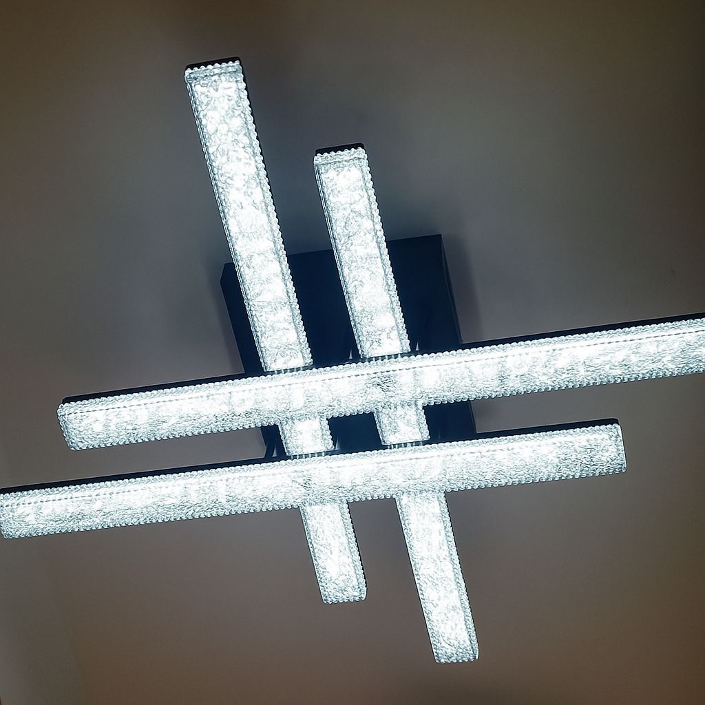 Lámpara de techo moderna con cuatro barras rectangulares revestidas de cristal en una habitación oscura.