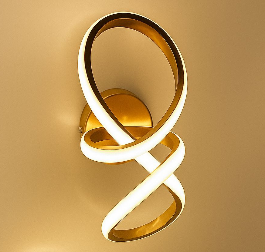 Aplique de pared en forma de remolino dorado y blanco que emite una luz brillante sobre una pared beige.
