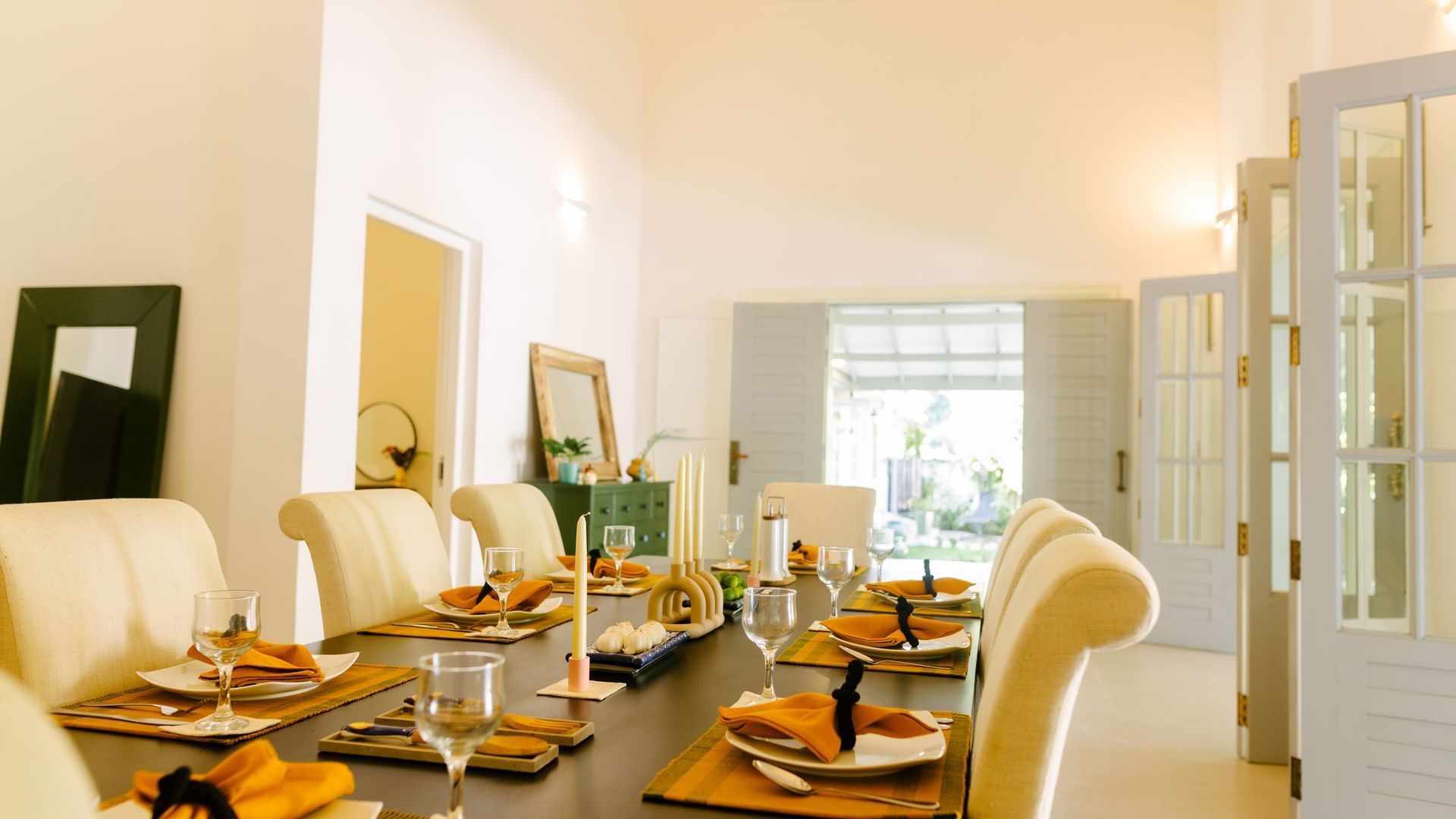 Long dining table set for a meal in a bright room with open doors to a garden.