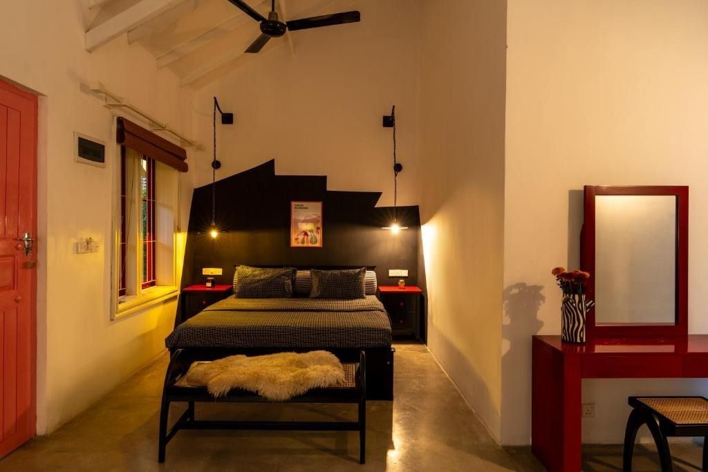 Bedroom with bed, red door, vanity, and black accents.