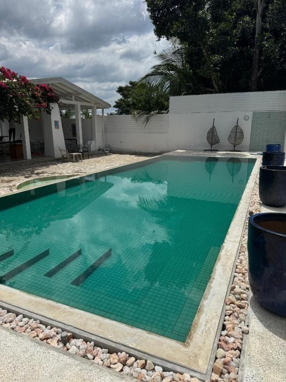 Swimming pool with teal water, steps, and white exterior. Cloudy sky reflected in water.