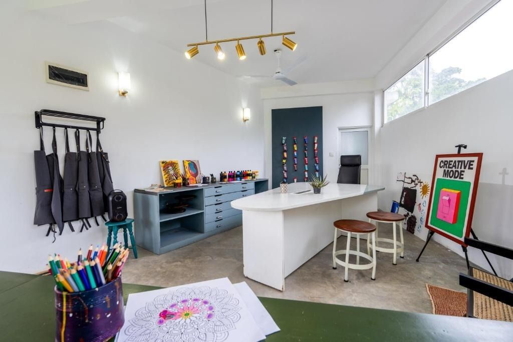 Art studio interior with a table, art supplies, and finished artwork.