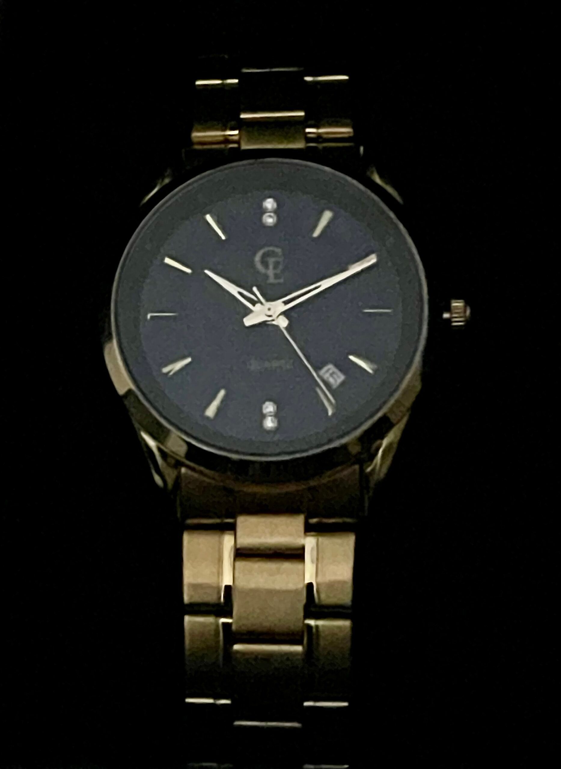 Gold wristwatch with a dark face.