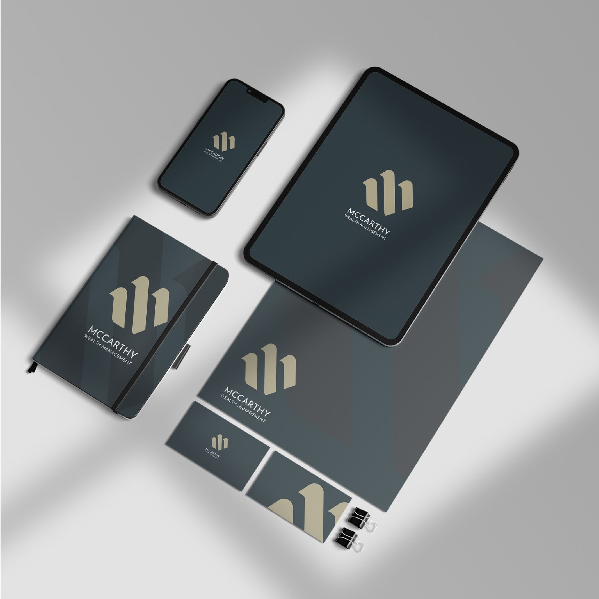 Branding mockup with phone, tablet, notebook, paper, and business cards featuring a gold logo on a dark background.