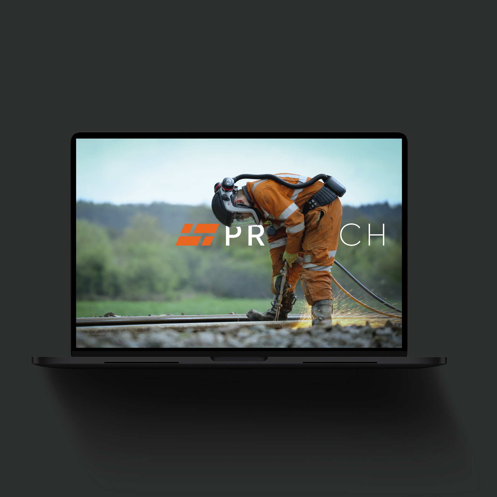 Person in protective gear welds train tracks, orange logo on screen.