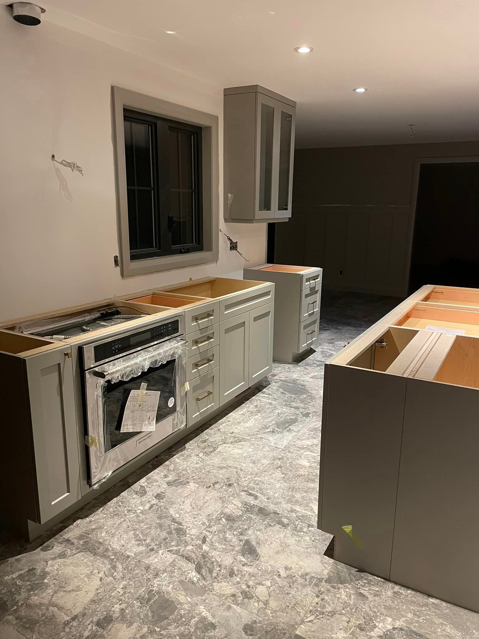 A kitchen with a stove , oven , cabinets and a window.