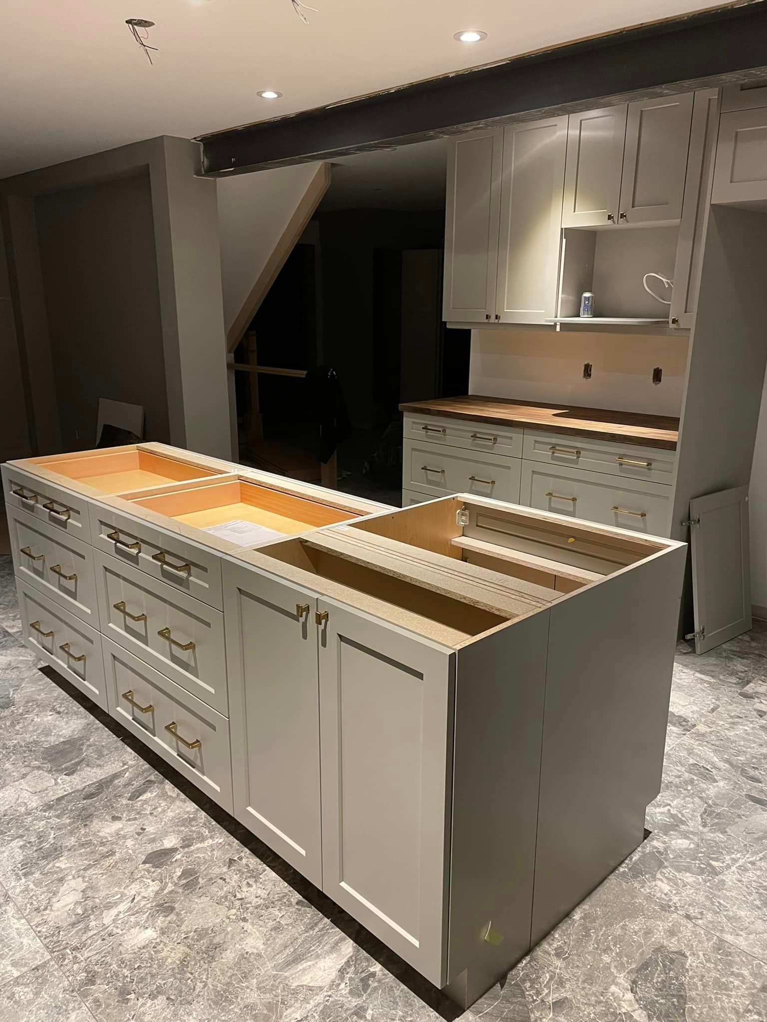 A kitchen with white cabinets and drawers is being built.