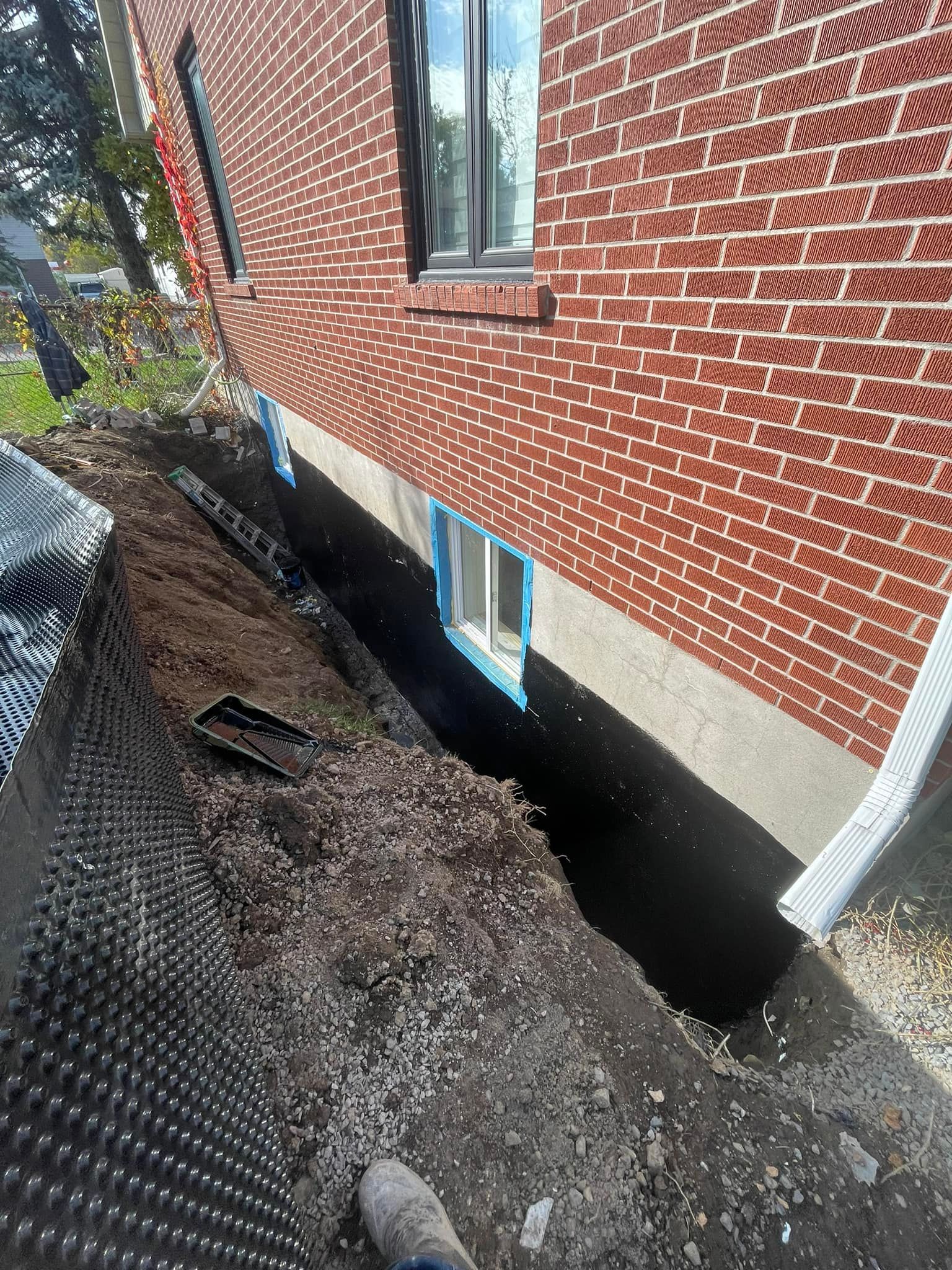 A person is digging a hole in the side of a brick building.