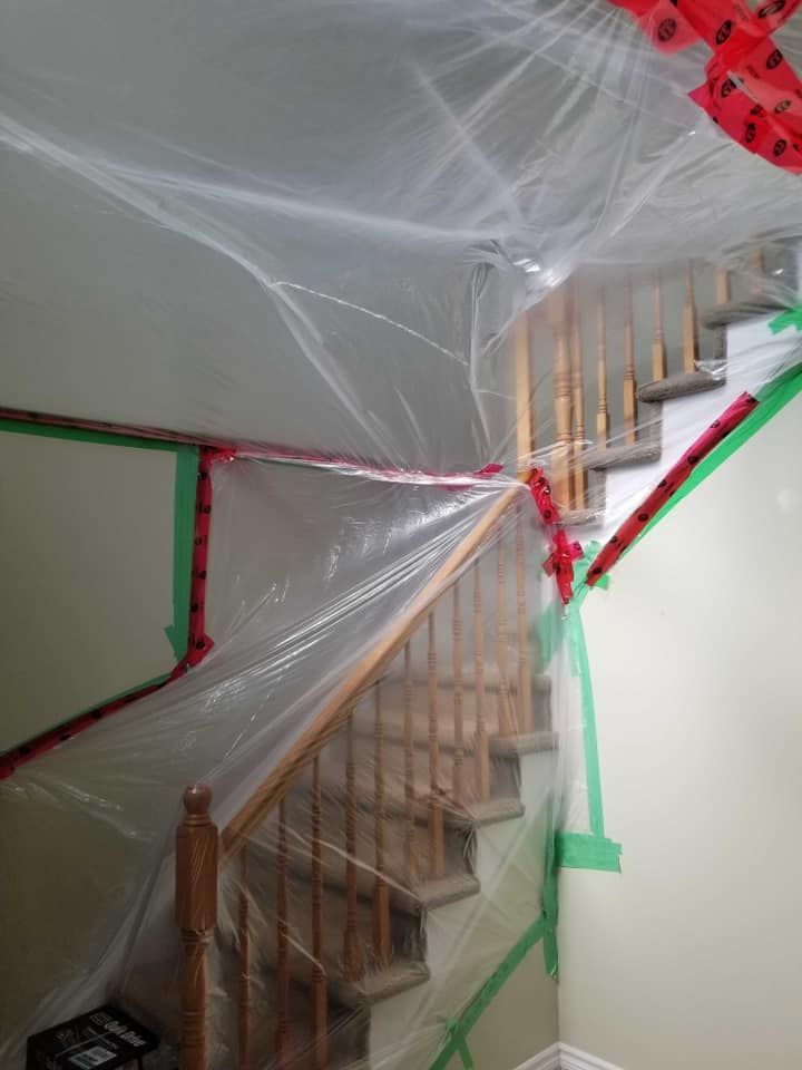 A staircase is covered in plastic and tape.